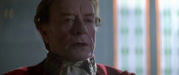 Movie still from “Ridicule” (1996), directed by Patrice Leconte – An old man wearing a neck tie and a red jacket; Close Up shot, Over the shoulder angle