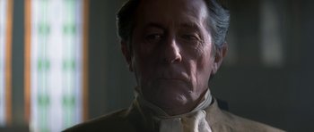 Movie still from “Ridicule” (1996), directed by Patrice Leconte – An older man wearing a white shirt and a brown jacket; Close Up shot, Low angle