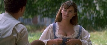 Movie still from “Ridicule” (1996), directed by Patrice Leconte – A beautiful woman in a white shirt and blue overalls standing next to a tree; Close Up shot, Over the shoulder angle