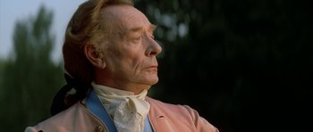 Movie still from “Ridicule” (1996), directed by Patrice Leconte – An older man wearing a pink jacket and a blue tie; Close Up shot, Low angle