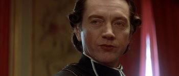 Movie still from “Ridicule” (1996), directed by Patrice Leconte – A person wearing a suit; Close Up shot, Low angle