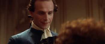 Movie still from “Ridicule” (1996), directed by Patrice Leconte – A person wearing a suit and tie; Close Up shot, Over the shoulder angle