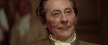 Movie still from “Ridicule” (1996), directed by Patrice Leconte – An older man wearing a white shirt and a brown jacket; Close Up shot, Over the shoulder angle