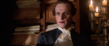 Movie still from “Ridicule” (1996), directed by Patrice Leconte – A man in a black jacket and a white shirt; Close Up shot, Over the shoulder angle