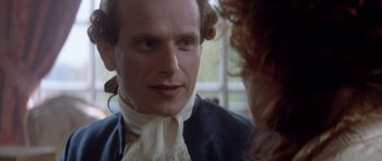 Movie still from “Ridicule” (1996), directed by Patrice Leconte – A person wearing a suit and tie; Close Up shot, Over the shoulder angle