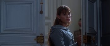 Movie still from “Ridicule” (1996), directed by Patrice Leconte – A woman standing in front of a white door; Medium shot, Over the shoulder angle