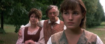 Movie still from “Ridicule” (1996), directed by Patrice Leconte – A woman and two men standing in front of each other; Close Up shot, Over the shoulder angle