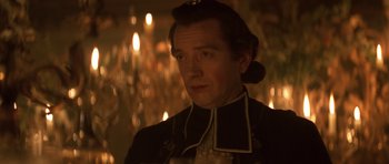 Movie still from “Ridicule” (1996), directed by Patrice Leconte – A person wearing a suit and tie; Close Up shot, Over the shoulder angle