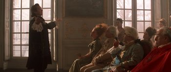 Movie still from “Ridicule” (1996), directed by Patrice Leconte – A group of people sitting in a room; Medium shot, Over the shoulder angle