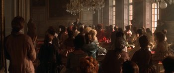 Movie still from “Ridicule” (1996), directed by Patrice Leconte – A large group of people gathered in a large room; Wide shot, High angle