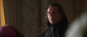 Movie still from “Ridicule” (1996), directed by Patrice Leconte – A person wearing a suit and tie; Close Up shot, Low angle