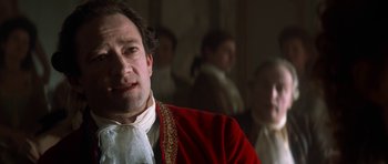 Movie still from “Ridicule” (1996), directed by Patrice Leconte – A person wearing a suit and tie; Close Up shot, Over the shoulder angle