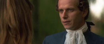 Movie still from “Ridicule” (1996), directed by Patrice Leconte – A person wearing a suit and tie; Close Up shot, Over the shoulder angle