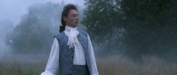 Movie still from “Ridicule” (1996), directed by Patrice Leconte – A man dressed in period clothing standing in a field; Medium shot, Low angle