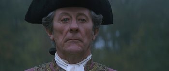 Movie still from “Ridicule” (1996), directed by Patrice Leconte – An older man wearing a black hat and a white shirt; Close Up shot, Low angle