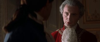 Movie still from “Ridicule” (1996), directed by Patrice Leconte – A person wearing a suit and tie; Close Up shot, Over the shoulder angle