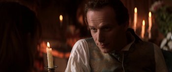 Movie still from “Ridicule” (1996), directed by Patrice Leconte – A person sitting in front of a candle; Close Up shot, Over the shoulder angle