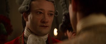 Movie still from “Ridicule” (1996), directed by Patrice Leconte – A person wearing a hat; Close Up shot, Over the shoulder angle