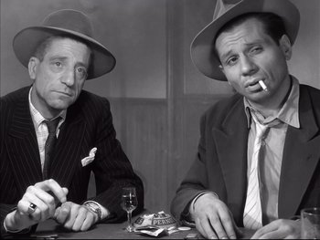 Movie still from “Rififi” (1955), directed by Jules Dassin – A couple of men sitting next to each other at a table; Medium shot, High angle