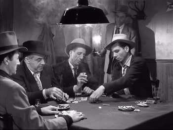 Movie still from “Rififi” (1955), directed by Jules Dassin – A black and white photo of a group of men sitting at a poker table; Medium shot, High angle
