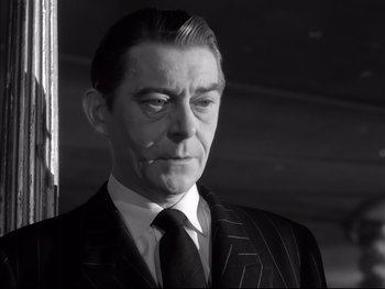 Movie still from “Rififi” (1955), directed by Jules Dassin – Black and white photograph of a man in a suit; Close Up shot, Low angle