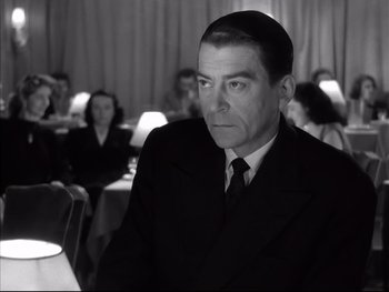 Movie still from “Rififi” (1955), directed by Jules Dassin – A black and white photo of a man in a suit and tie; Close Up shot, Over the shoulder angle