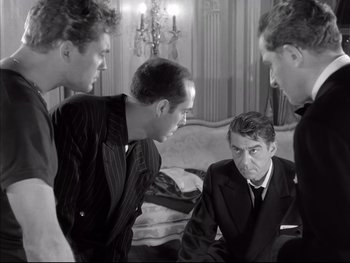 Movie still from “Rififi” (1955), directed by Jules Dassin – A group of young men standing around a man in a suit; Medium shot, Over the shoulder angle