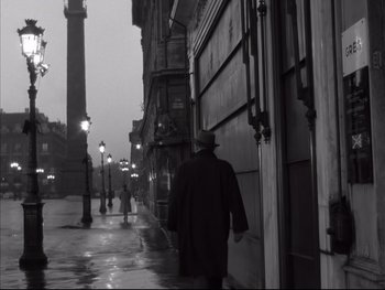 Movie still from “Rififi” (1955), directed by Jules Dassin – A man walking down a street in the rain; Wide shot, Low angle