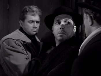 Movie still from “Rififi” (1955), directed by Jules Dassin – A man in a hat and a man in a trench coat; Close Up shot, Over the shoulder angle