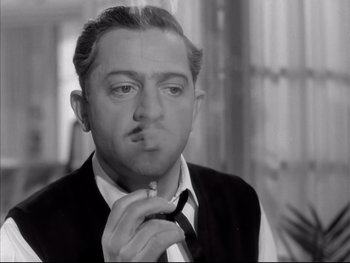 Movie still from “Rififi” (1955), directed by Jules Dassin – A black and white photo of a man smoking a cigarette; Close Up shot, Low angle