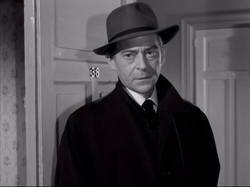 Movie still from “Rififi” (1955), directed by Jules Dassin – A man wearing a hat and a coat; Close Up shot, Low angle