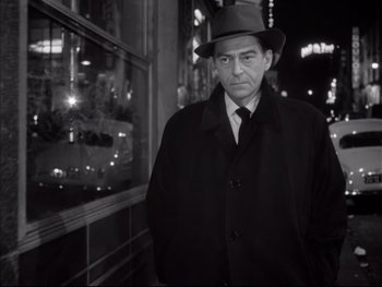 Movie still from “Rififi” (1955), directed by Jules Dassin – A black and white photo of a man wearing a hat; Medium shot, Low angle