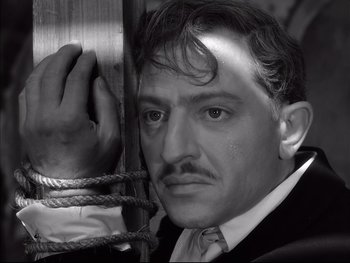 Movie still from “Rififi” (1955), directed by Jules Dassin – A black and white photo of a man with a mustache; Close Up shot, Low angle