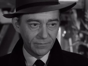 Movie still from “Rififi” (1955), directed by Jules Dassin – A black and white photo of a man wearing a hat; Close Up shot, Low angle