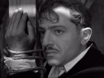 Movie still from “Rififi” (1955), directed by Jules Dassin – A black and white photo of a man with a tie around his neck; Close Up shot, Low angle