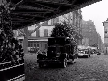 Movie still from “Rififi” (1955), directed by Jules Dassin – An old car is parked under a bridge in a city; Wide shot, High angle