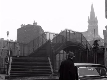 Movie still from “Rififi” (1955), directed by Jules Dassin – A man in a hat is walking down the stairs; Wide shot, Low angle