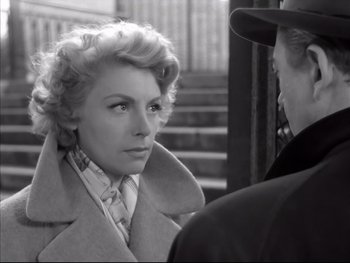 Movie still from “Rififi” (1955), directed by Jules Dassin – An old photo of a woman in a trench coat looking at a man; Close Up shot, Over the shoulder angle
