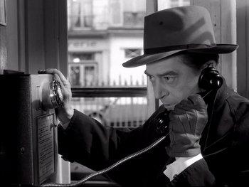 Movie still from “Rififi” (1955), directed by Jules Dassin – A man wearing a hat is talking on a phone; Close Up shot, High angle