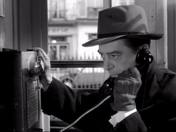 Movie still from “Rififi” (1955), directed by Jules Dassin – A black and white photo of a man talking on a phone; Close Up shot, Low angle