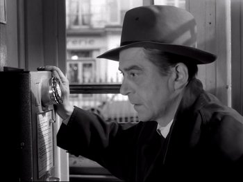 Movie still from “Rififi” (1955), directed by Jules Dassin – A black and white photo of a man wearing a hat; Close Up shot, Low angle