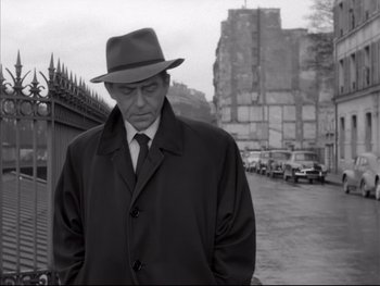 Movie still from “Rififi” (1955), directed by Jules Dassin – A black and white photo of a man wearing a hat and a coat; Medium shot, Low angle