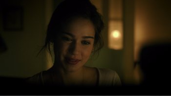 Movie still from “Rings” (2017), directed by F. Javier Gutiérrez – A young woman looking at the camera in a dimly - lit room; Close Up shot, Over the shoulder angle