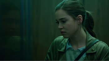 Movie still from “Rings” (2017), directed by F. Javier Gutiérrez – A young woman is looking down while standing in front of a wall; Close Up shot, Over the shoulder angle