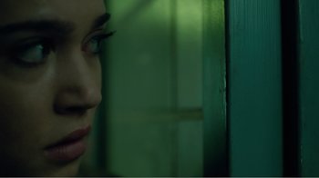Movie still from “Rings” (2017), directed by F. Javier Gutiérrez – A woman's face in front of a green door; Extreme Close Up shot, Over the shoulder angle