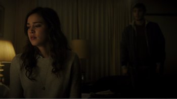 Movie still from “Rings” (2017), directed by F. Javier Gutiérrez – Two people standing in a dark room , one of whom is looking at the camera; Medium shot, Over the shoulder angle