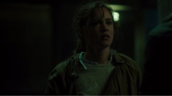 Movie still from “Rings” (2017), directed by F. Javier Gutiérrez – A woman in a green jacket is standing in the dark; Close Up shot, Over the shoulder angle