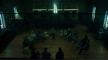 Movie still from “Rings” (2017), directed by F. Javier Gutiérrez – A group of people sitting in a circle in front of a stage; Extreme Wide shot, High angle