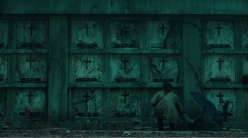 Movie still from “Rings” (2017), directed by F. Javier Gutiérrez – A man kneeling down in front of a wall with crosses on it; Extreme Wide shot, High angle