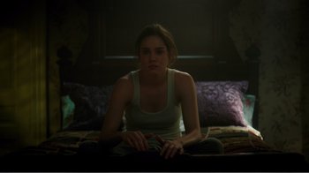 Movie still from “Rings” (2017), directed by F. Javier Gutiérrez – A woman sitting on the ground in a dark room; Medium shot, Low angle